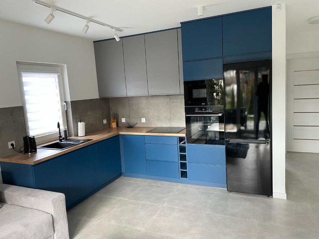 兰卡特Apartament Luna的厨房配有蓝色橱柜和黑色冰箱。