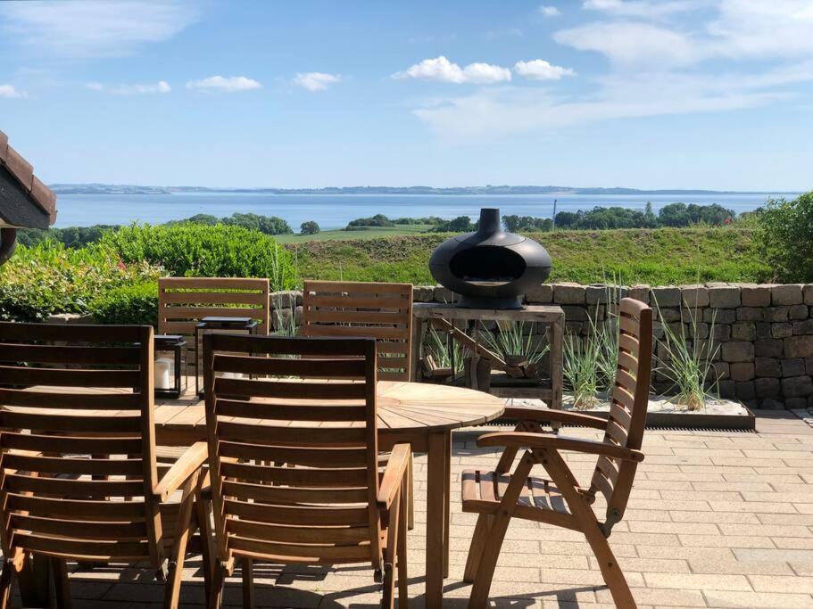 伦德Luxury house with breathtaking sea view of Mols的天井上配有桌子和两把椅子及烧烤架