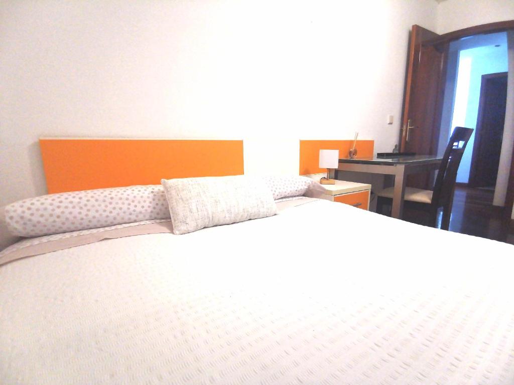 马里亚诺Habitación cerca del aeropuerto的一间卧室配有一张白色大床和橙色床头板