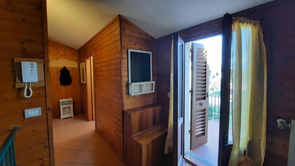 菲利内瓦尔达诺La Mansarda的走廊上配有电视,门通往房间