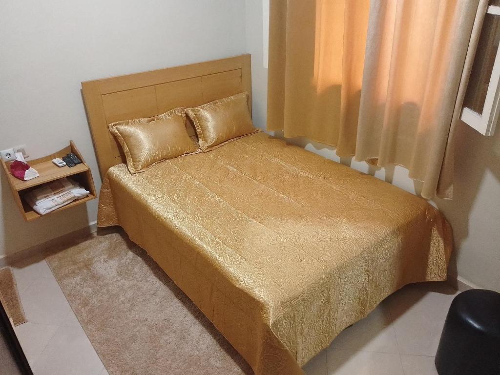 海尼夫拉Maison d'hôte Najah的一间小卧室,配有带金色床单和枕头的床