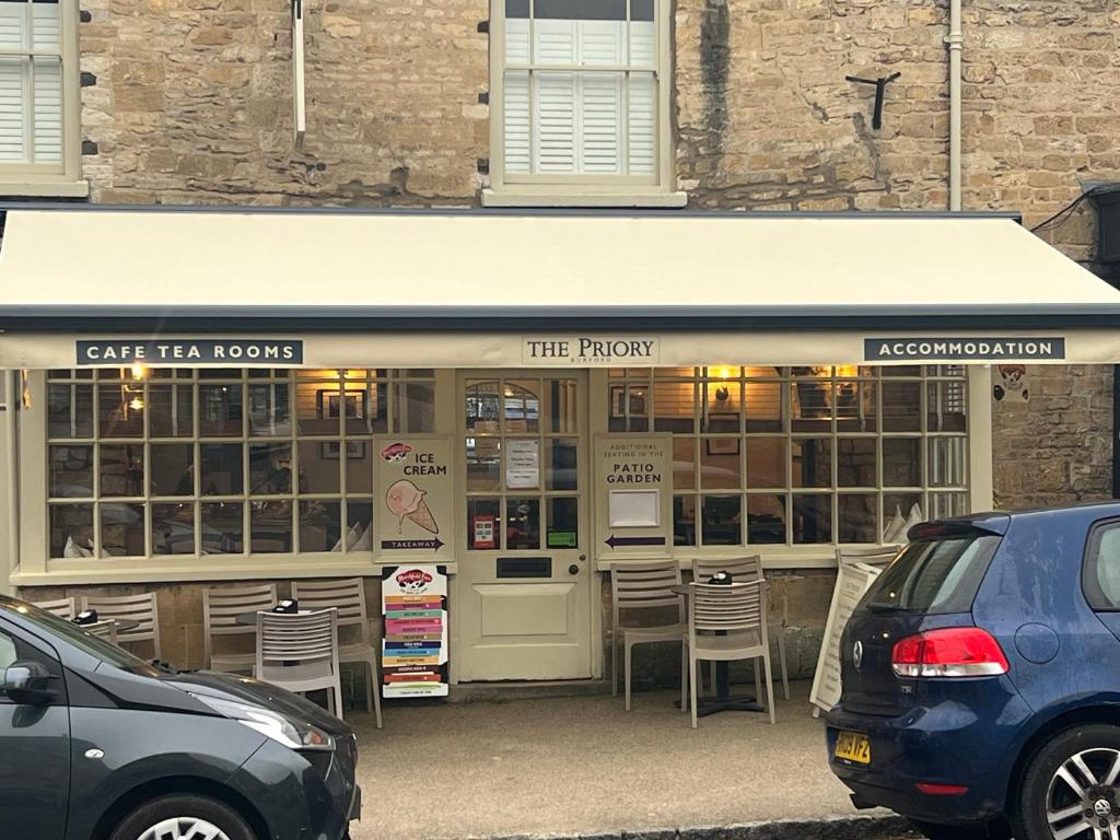 伯福德Priory Tearooms Burford with Rooms的大楼前带椅子的餐厅