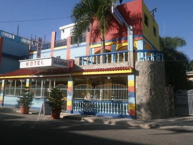 博卡奇卡Hotel Mango的一座五彩缤纷的建筑,前面有一棵棕榈树