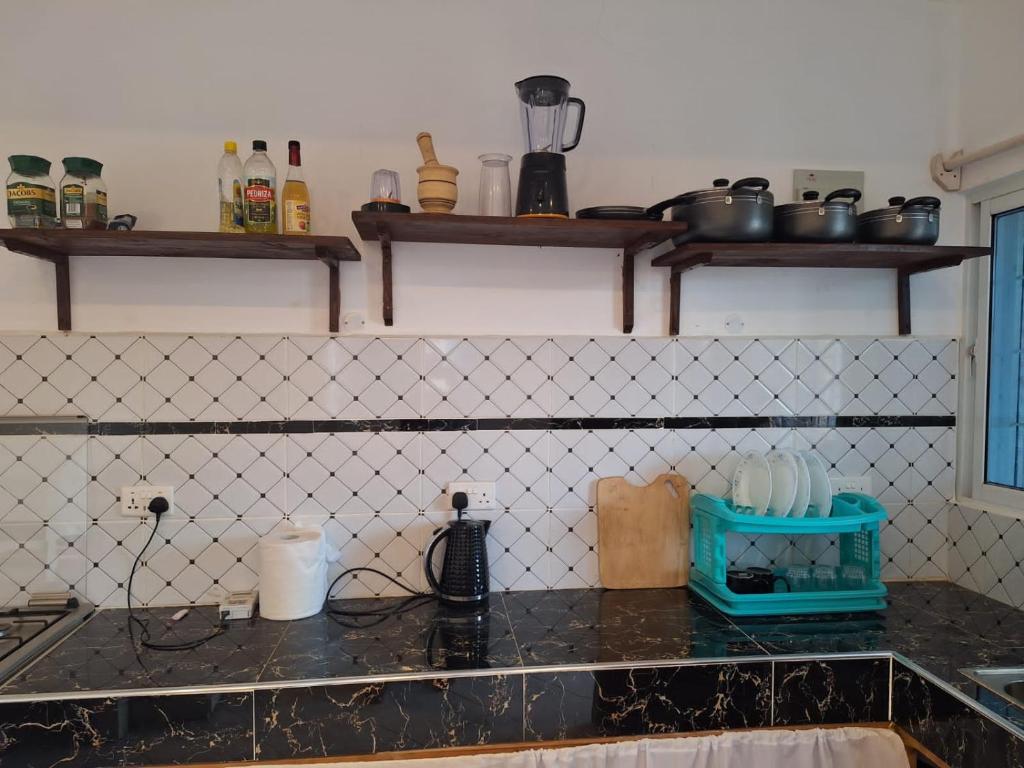 乌昆达Cool breeze的厨房配有黑色台面和墙上的架子