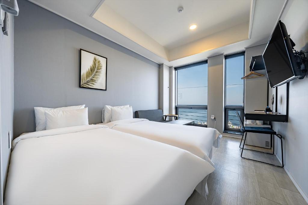 束草市Stay Hostel的酒店客房设有两张床和电视。