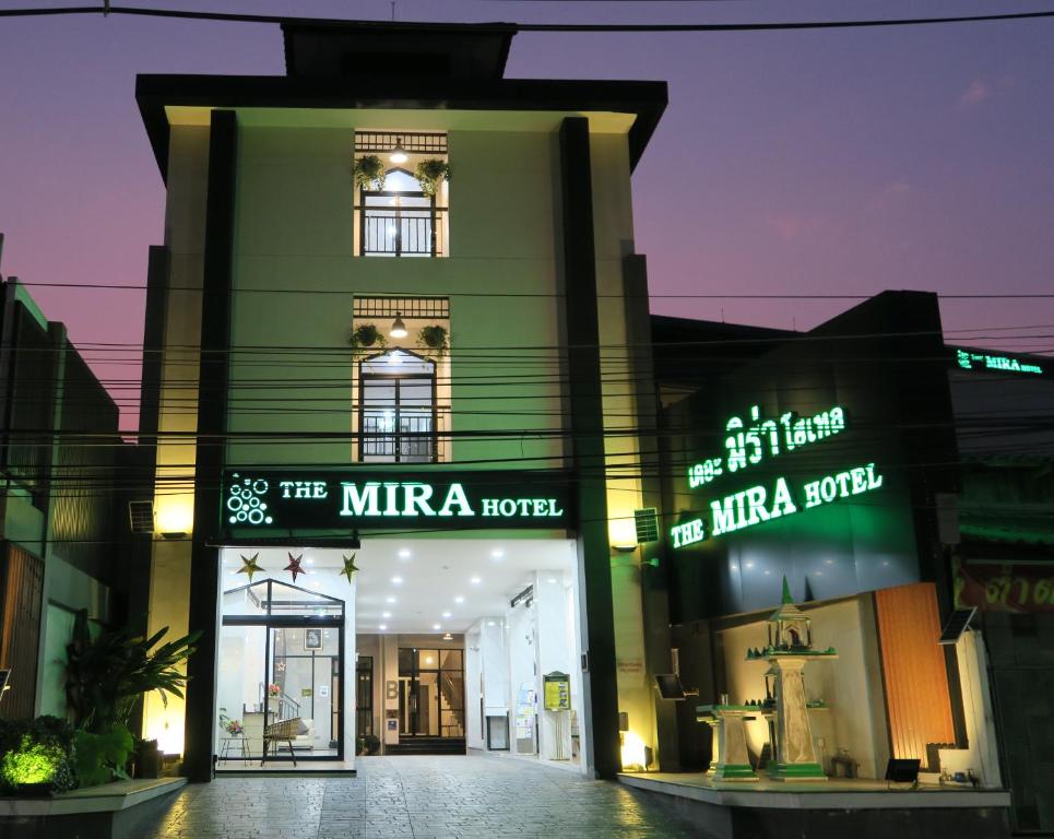 清莱The Mira Hotel Chiang Rai的前面有 ⁇ 虹灯标志的绿色建筑