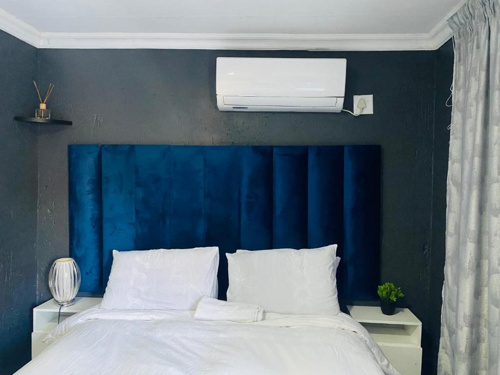 察嫩Executive Galaxy Guest House Nkowankowa Extension 2的一间卧室配有蓝色床头板和白色的床