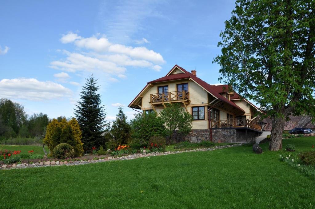 SukturiViesu nams Bezdubeņi的前面有绿色草坪的大房子