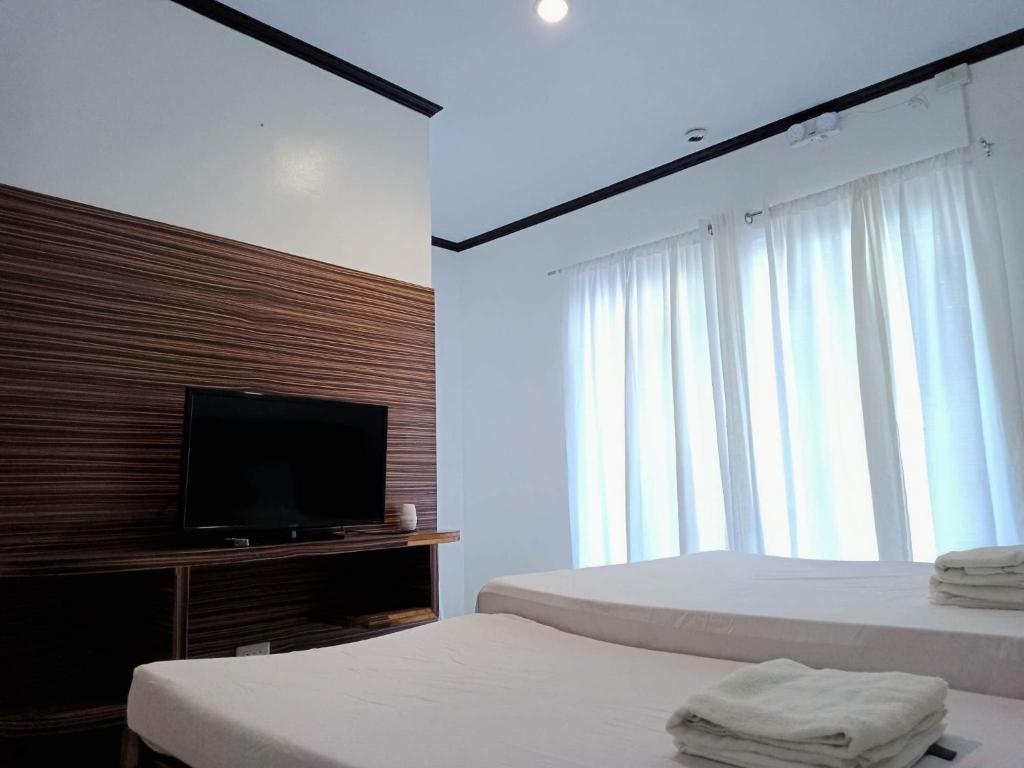 长滩岛VILLA LOURDES RESORT的一间卧室配有两张床和一台平面电视