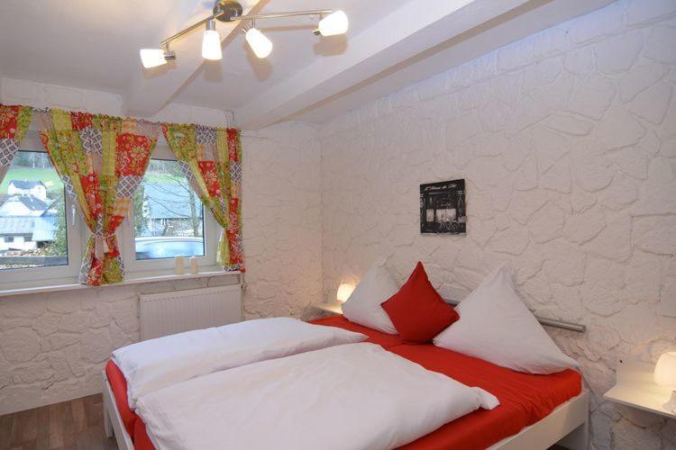 施马伦贝格Haus Oberkirchen的一间卧室配有带白色和红色枕头的床
