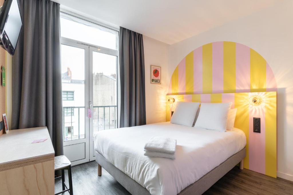 南特DEMAIN Hôtel & Conciergerie的酒店客房设有一张床和一个大窗户
