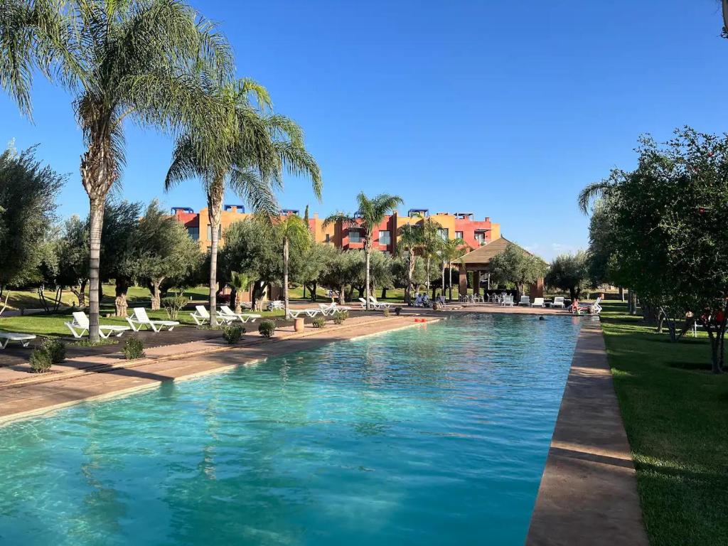 马拉喀什Appartement avec Solarium Privé au Vizir Résidence Prestigieuse avec Accès au Parc的棕榈树公园内的游泳池