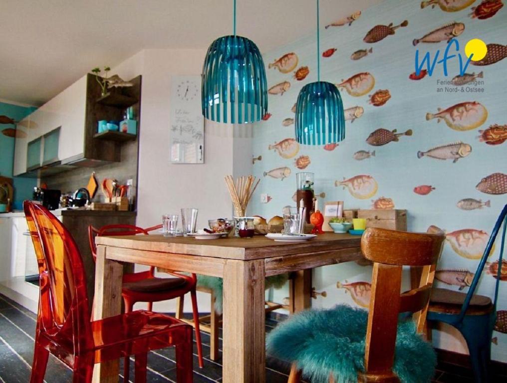 万根沃格Bootshaus in den Duenen - 1 Ferienwohnung "Unter Fischen"的厨房配有带红色椅子的木桌