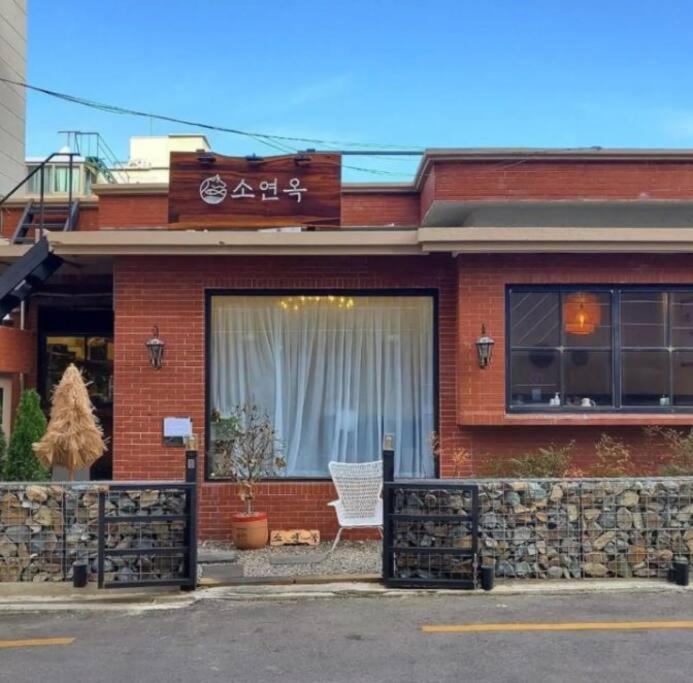 釜山Chille with free parking #Jeonpo station 2min #new #cozy #jazzbar #laundary everyday #healing的红砖建筑,窗户上设有白色椅子