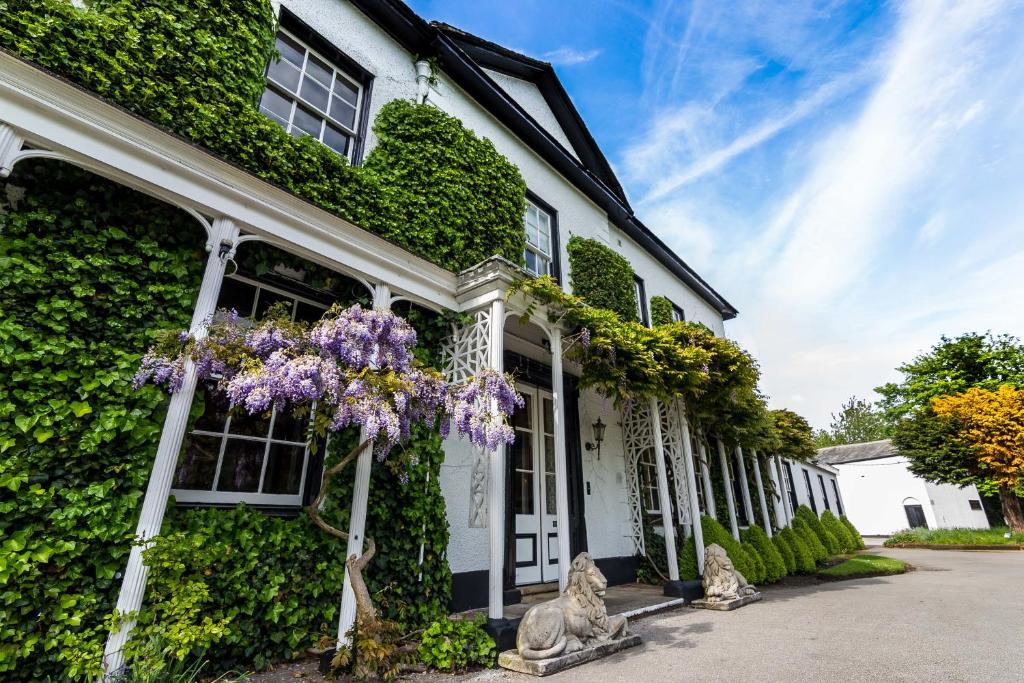 沃灵顿斯坦森洛奇酒店的白色的房子,有紫色花朵覆盖着常春藤