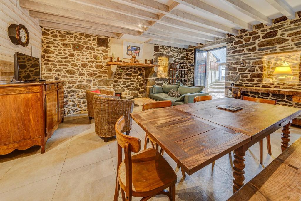 圣马洛Minihic - Belle maison 3 chambres- Proche Mer的一间设有木桌和石墙的用餐室