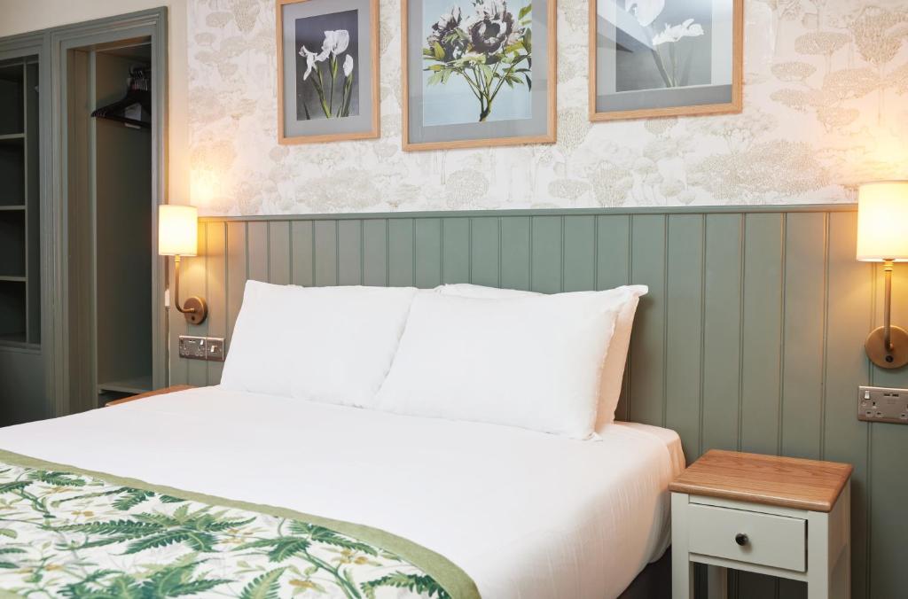 罗克瑟姆The Kings Head Wroxham by Greene King Inns的卧室配有白色的床,墙上挂有图片