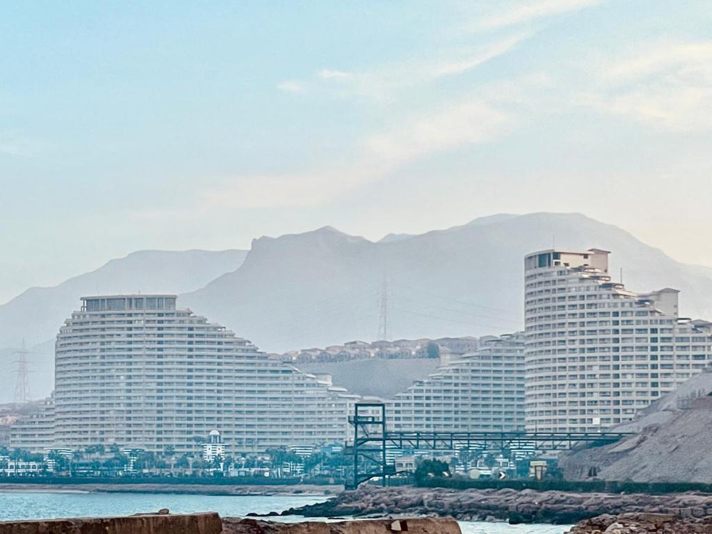 艾因苏赫纳Pyramids Porto El Sokhna Familis Only的两座以群山为背景的大型酒店建筑