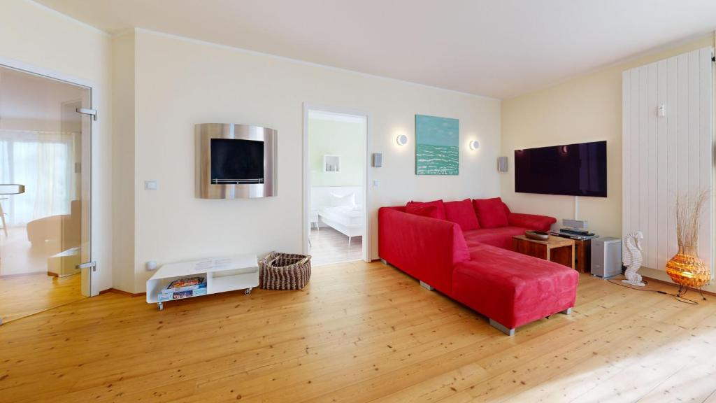 宾茨Villa am Kurpark的客厅配有红色沙发和平面电视
