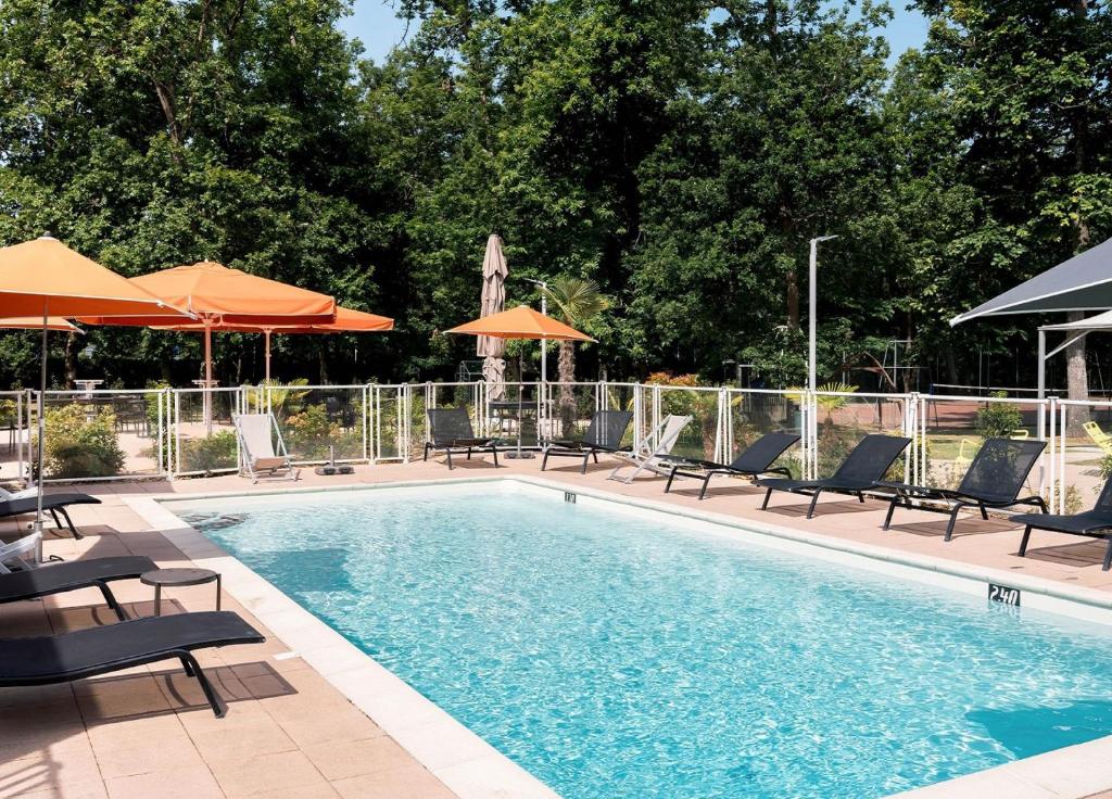 奥尔良奥尔良南拉索斯诺富特酒店的一个带躺椅和遮阳伞的游泳池