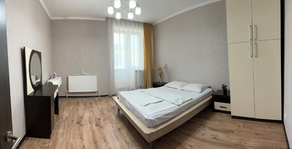 乌拉尔斯克Уютная рядом с парком的卧室配有白色的床和镜子