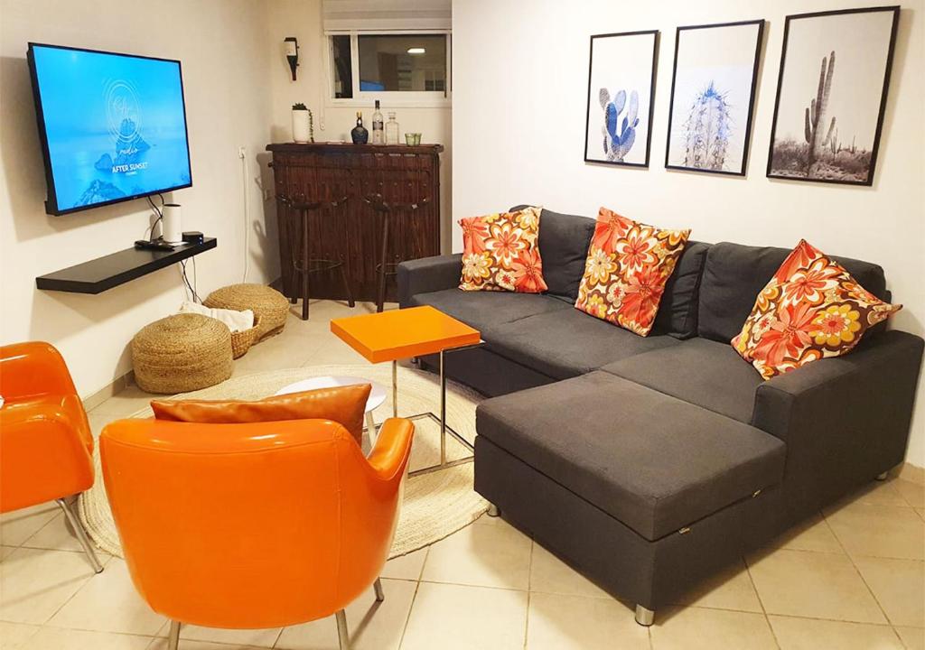 Gan H̱ayyimSpacious and Peaceful 2BD with a Garden & Parking的客厅配有黑色沙发和橙色椅子