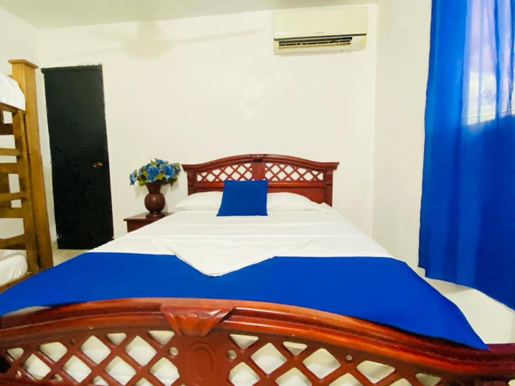圣玛尔塔HOSTAL OLAS CLUB DE NEGUANJE -TAYRONA的一间卧室配有一张带蓝色枕头的床