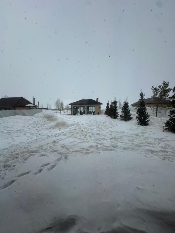 KuprinkaБозайгыр的一座有雪盖的院子,后面有一座房子