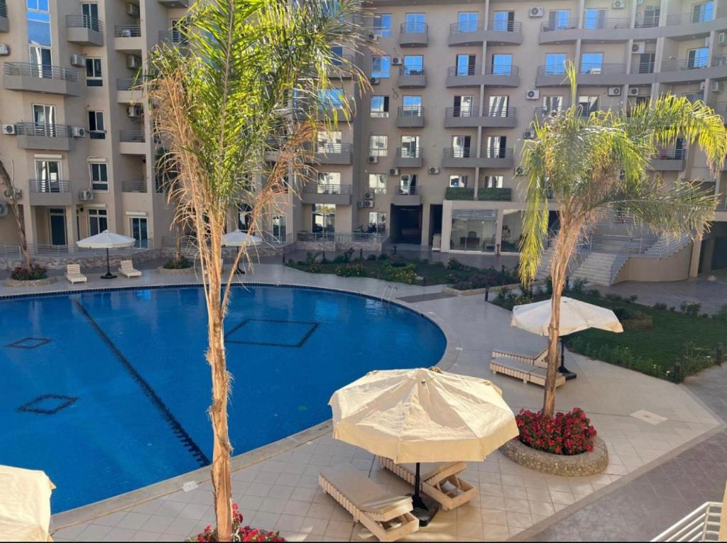 赫尔格达Princess Resort的一座大楼前的游泳池,里面设有遮阳伞和棕榈树
