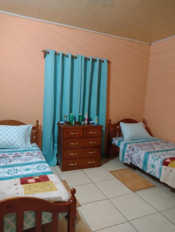 ArimaTessa's Inn的一间卧室配有两张床、一个梳妆台和蓝色窗帘