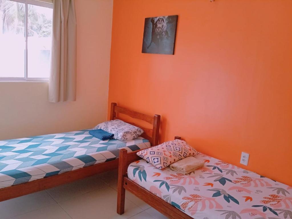 帕拉库鲁Pousada Vista Verde的橙色墙壁客房中的两张单人床