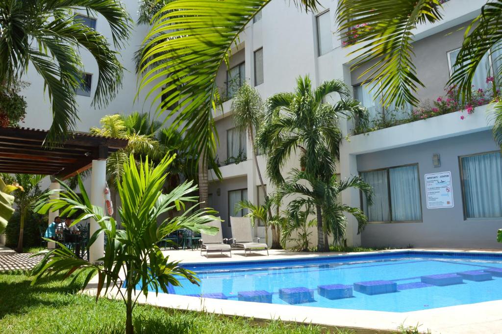 坎昆亲密套房酒店的棕榈树建筑前的游泳池