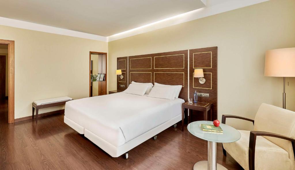 巴达霍斯NH埃斯特雷马杜拉赌场大酒店的卧室配有白色的床、桌子和椅子