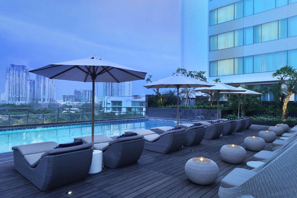 雅加达DoubleTree by Hilton Jakarta Kemayoran的游泳池旁的一排椅子和遮阳伞