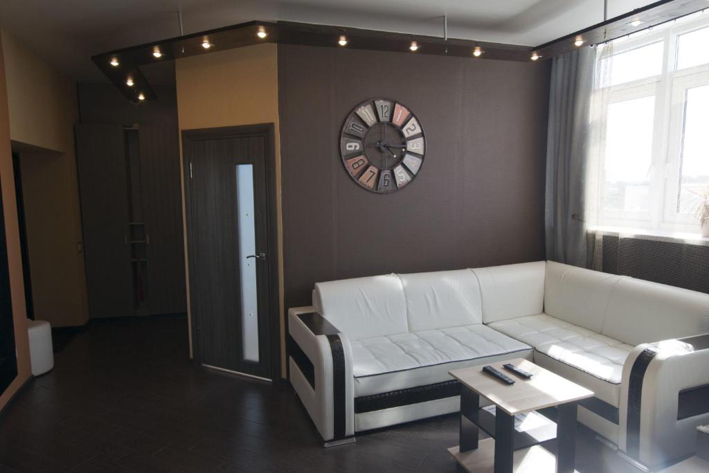 下诺夫哥罗德纳特维尔区公寓酒店的客厅配有白色沙发和时钟