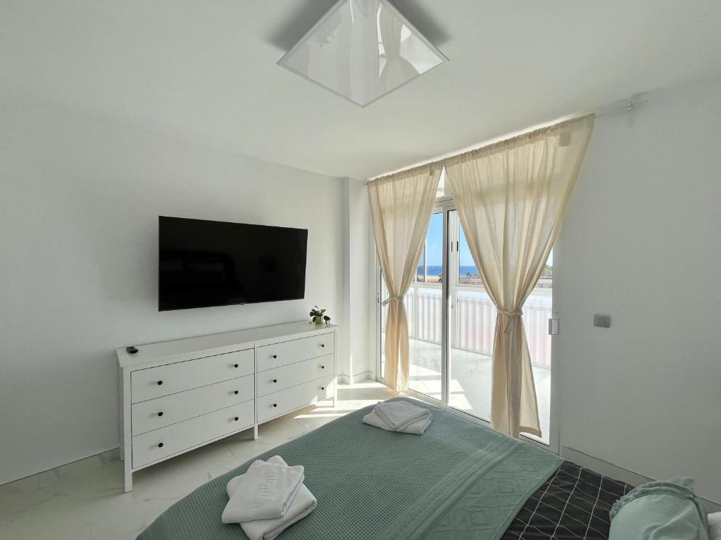 莫罗德哈布雷Jandia Beach Apartment 2的一间卧室配有电视和一张带梳妆台的床