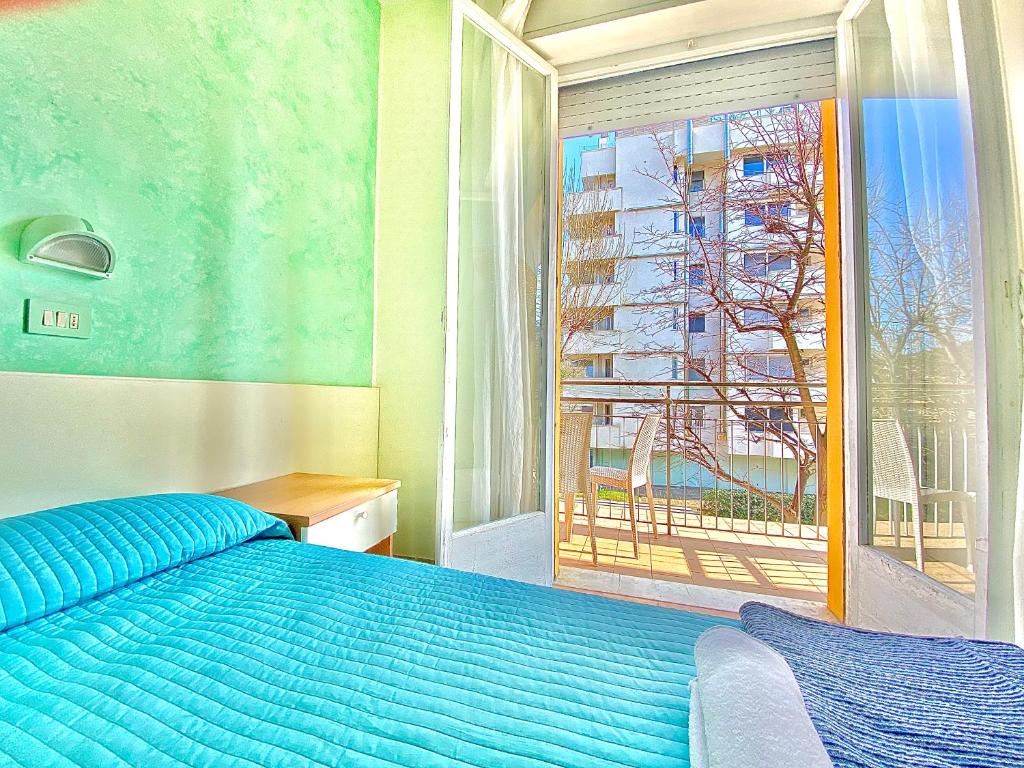 里米尼Hotel Majorca Nuova Gestione Rimini 100 m dalla spiaggia的一间卧室设有蓝色的床和窗户。