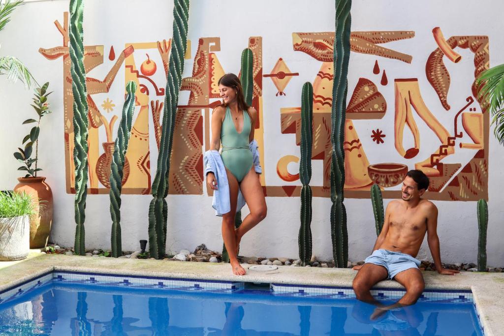 梅里达Casa Encuentro De Joaquín Garcia的站在游泳池旁的男人和女人