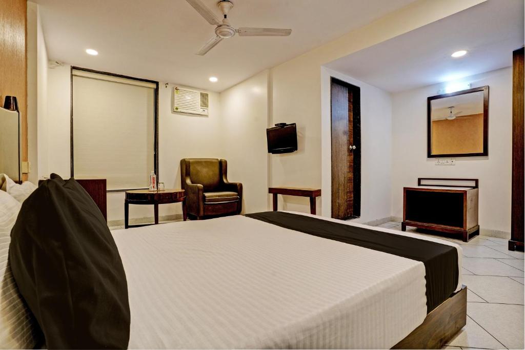 SaravliSuper OYO Flagship Hotel Golden Nest的一间卧室配有一张床、一台电视和一把椅子