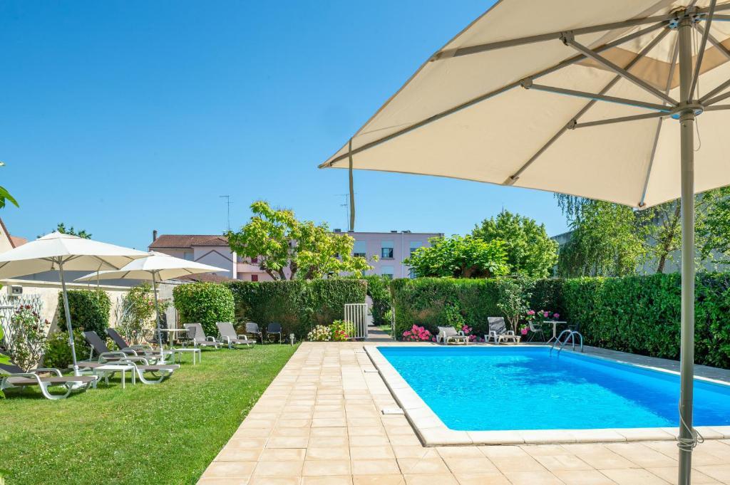 贝尔热拉克Brit Hotel Europ Bergerac的一个带遮阳伞的游泳池,位于带椅子的庭院旁