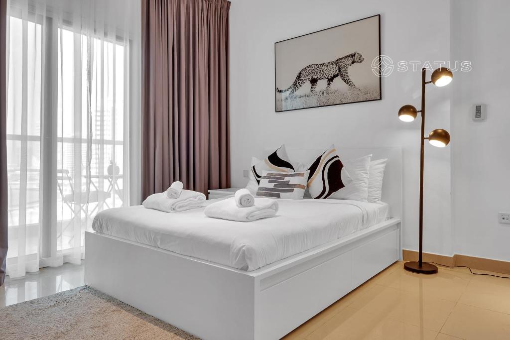 迪拜Sleek Studio - Red Residence-L8 - Near ISD Stadium的白色卧室,配有一张白色的床,并画有马的画面
