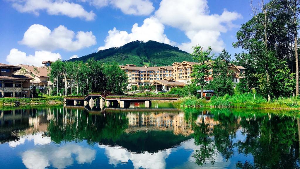 抚松县长白山万达锦华套房酒店 的一座建在山中湖中的建筑的反射