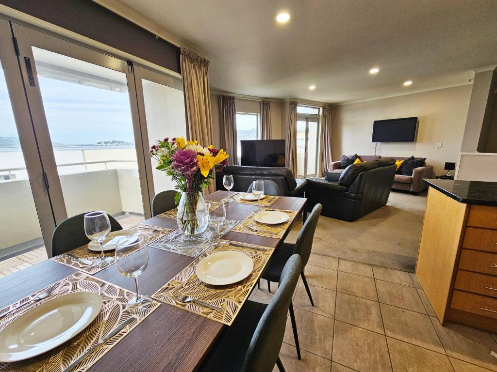 惠灵顿Executive, Spacious & Modern Home, 8 Beds!的用餐室配有带酒杯和鲜花的桌子