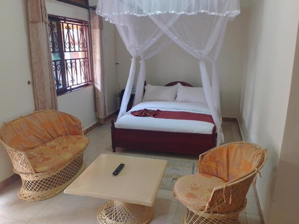 姆巴拉拉Acacia Country Inn的一间卧室配有一张床、两把椅子和一张桌子