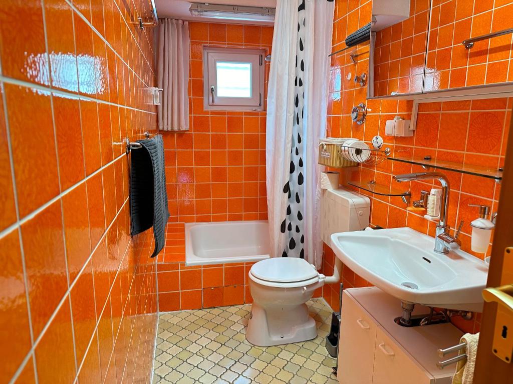 加格瑙MELLoWY Monteure, TV, Küche, Bad的橙色浴室设有卫生间和水槽