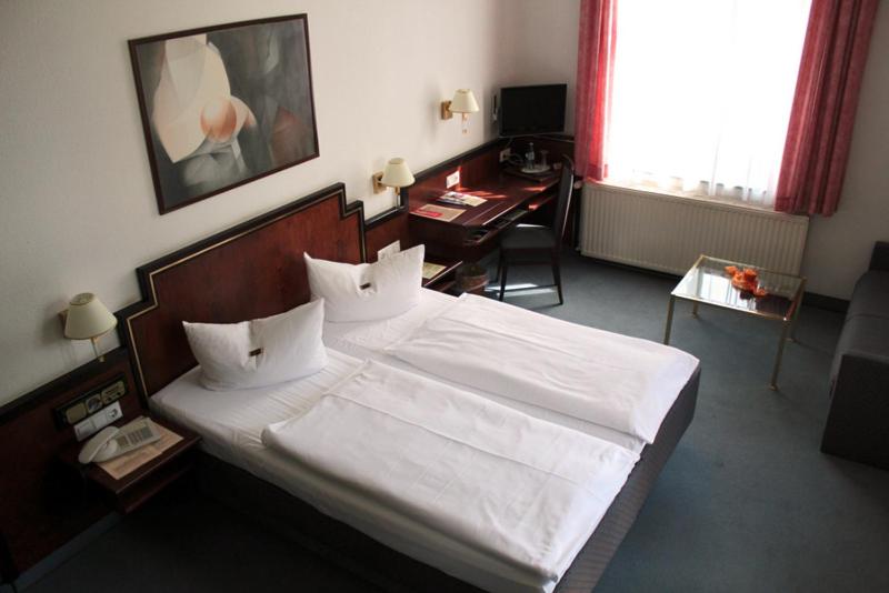 德累斯顿基平酒店的卧室配有一张大白色的床和书桌