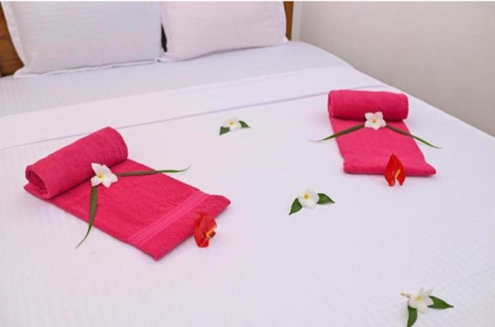 尼甘布Negombo Royal Villa by Hotel Oviniru的床上有两条粉红色的毛巾和鲜花