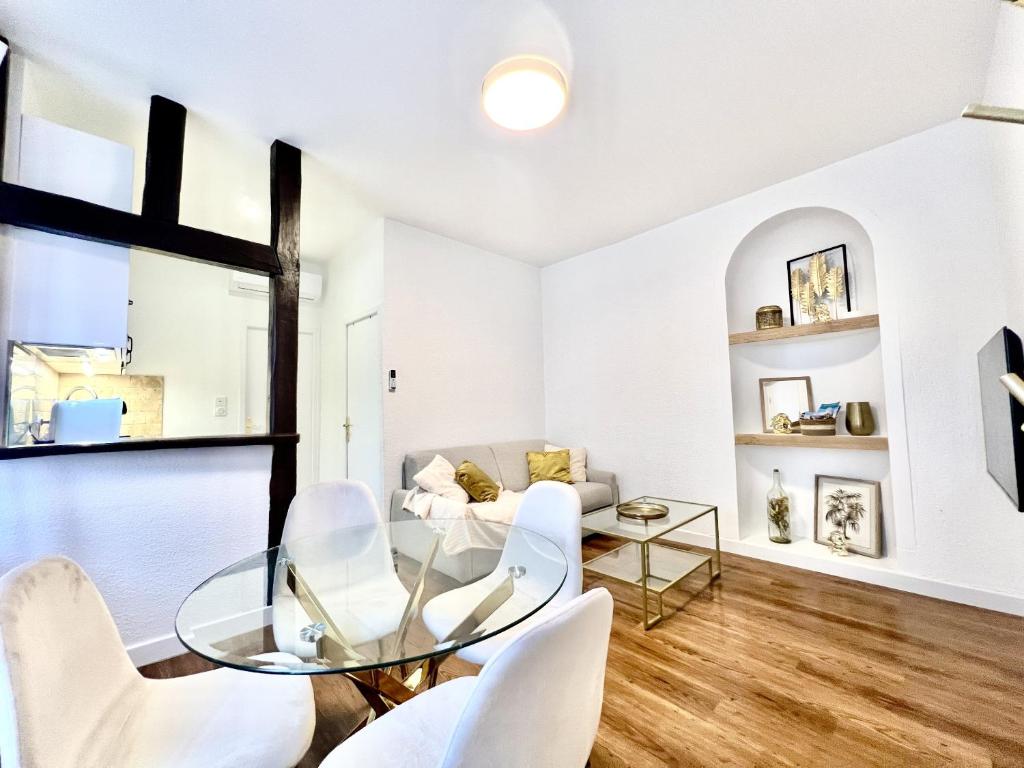 罗莫朗坦Les Logis d'Esmeralda-Des appartements au charme intemporel的客厅配有玻璃桌和白色椅子