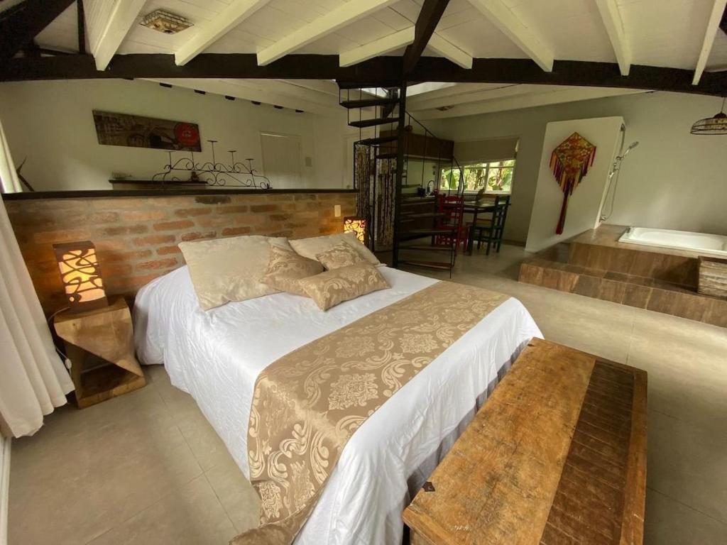 佩尼多Dingo - Refugio romântico em meio à natureza的一间卧室设有一张大床和一张木凳