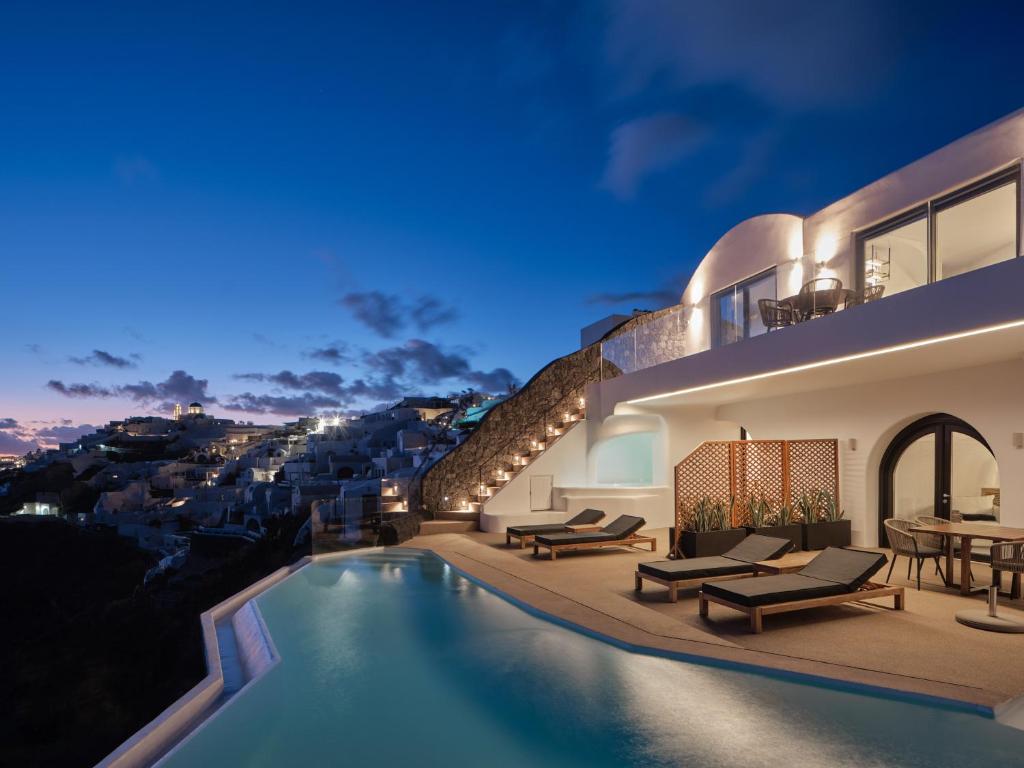 伊亚Olvos Luxury Suites的夜间带游泳池的别墅